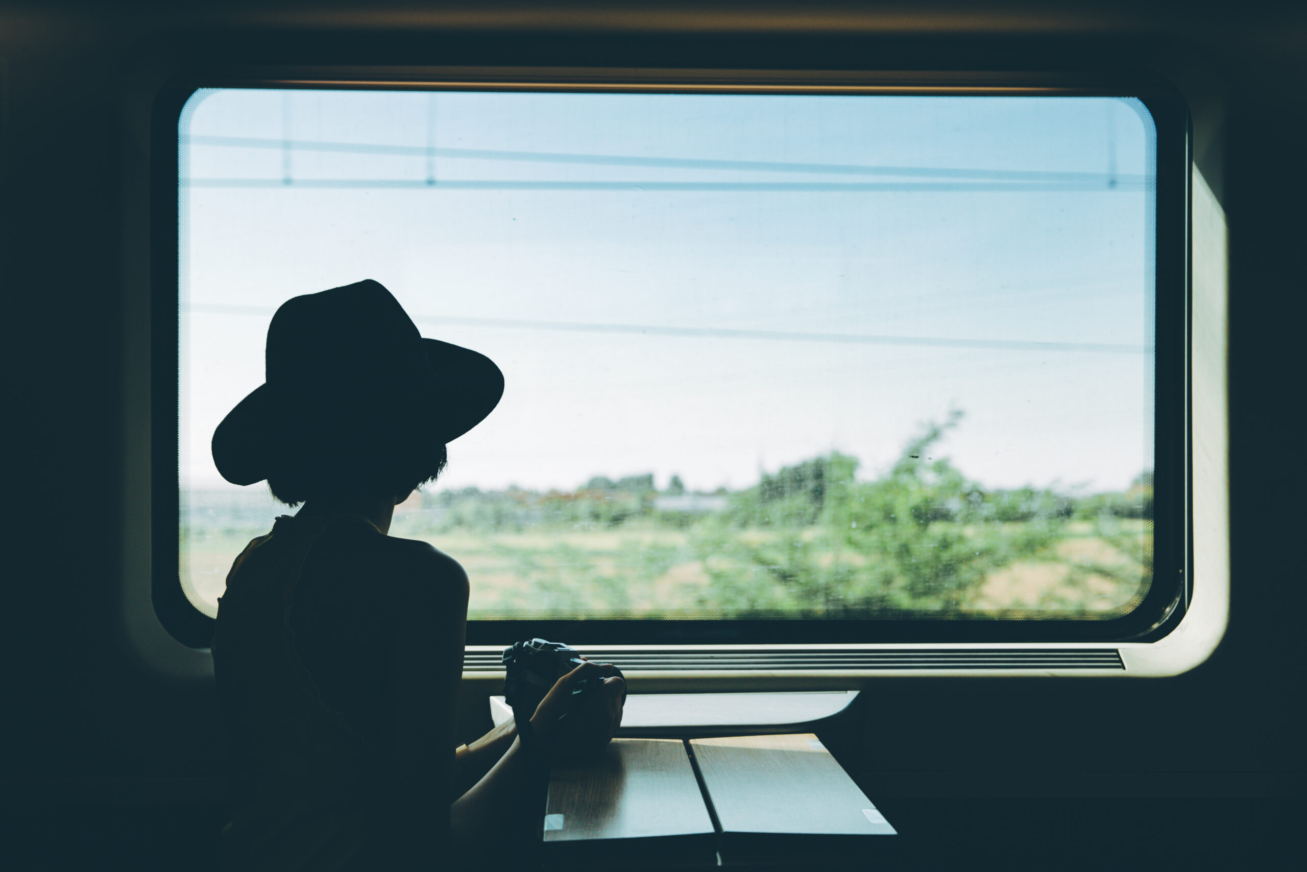 silhouette of young traveler looking out a window of a train.