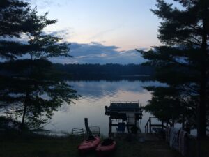 calm lake, evening just arrived, two kayaks leaning together like good friends on the shore.